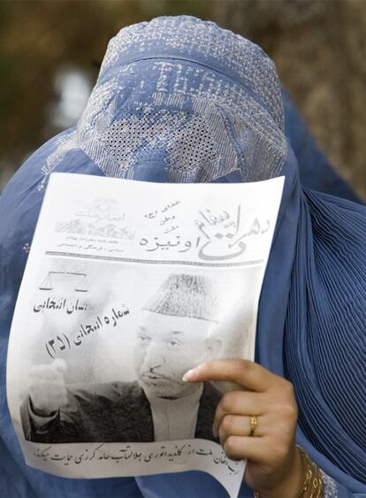 Una mujer con la burka sostiene un cartel electora del candidato a la reelección presidencial, Hamid Karzai.