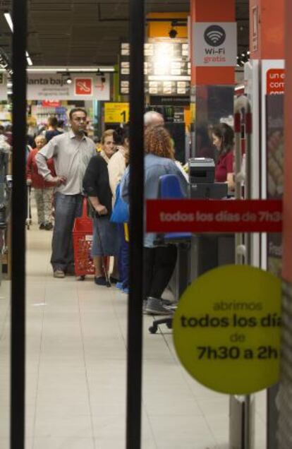 Cola de clientes ante la caja de un supermercado de la cadena Carrefour, situado en la plaza de Lavapiés de Madrid, que abre de 7.30 a las 2.00 horas.