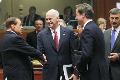 El primer ministro griego, Yorgos Papandreu (en el centro), saluda a Berlusconi el jueves  en Bruselas.