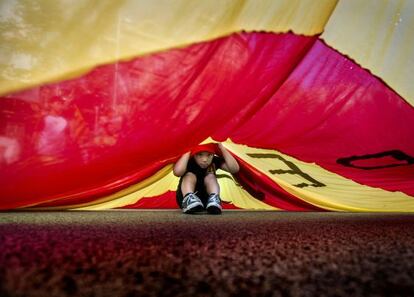 Un nen treu el cap sota una inmensa senyera en la manifestaci&oacute; de la diada de l&acute;Onze de Setembre d&acute;enguany.