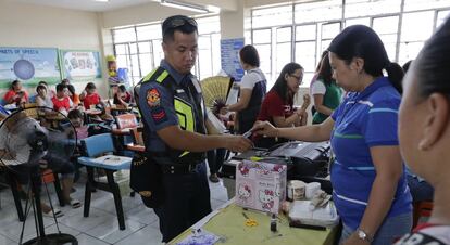 Un policía deposita su vota en la urna en Manila, Filipinas.