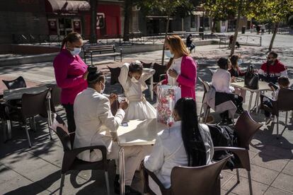 Una familia celebra el sábado la comunión de su hija en el bar La Ardilla, en Villa de Vallecas (Madrid). Desde el viernes por la noche, los habitantes de la capital y de nueve municipios aledaños solo pueden salir de su localidad en determinados casos, como ir a trabajar o estudiar, acudir al médico y atender a personas dependientes.