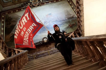 Un manifestante sujeta una bandera en la que se puede leer "Trump is my president" (Trump es mi presidente), dentro del Capitolio.