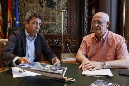 El presidente de la Generalitat valenciana, Carlos Mazón (i), muestra el libro del Plan de Recuperación de la dana al nuevo alcalde de Paiporta, Vicent Císcar (d), en el Palau de la Generalitat.