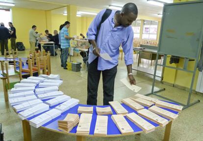 Paapa, un inmigrante senegalés, observa ayer las papeletas en un colegio electoral de Bilbao.