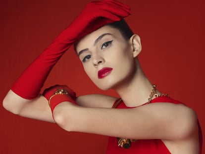 Vestido ajustado sin mangas realizado 
en lana y elastane rojo de CH Carolina Herrera, guantes largos de 
El Corte Inglés, pulsera vintage de oro con brillantes de Bárcena Joyas y collar dorado con forma de flor de Marina Rinaldi por Stella Jean. La modelo lleva la nueva crema labial Ecstasy Shine nº 400, 
de Giorgio Armani Beauty (35 euros), que hidrata como un bálsamo con el brillo de un gloss. 
