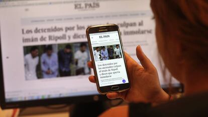 Una lectora de El Pa&iacute;s consulta la p&aacute;gina en su tel&eacute;fono m&oacute;vil.