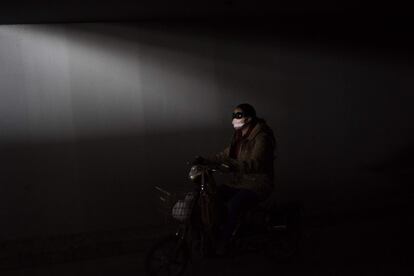 Una mujer monta su bicicleta en una carretera de circunvalación de Pekín (China).