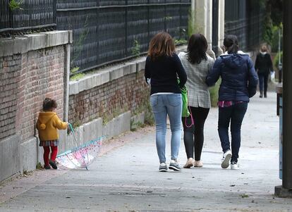 Una niña juega con un paraguas acompañada de varios adultos, en una calle de Madrid este martes. Desde que comenzó el decreto del estado de alarma, el 14 de marzo, 8,3 millones de menores permanecen encerrados en sus casas en España.