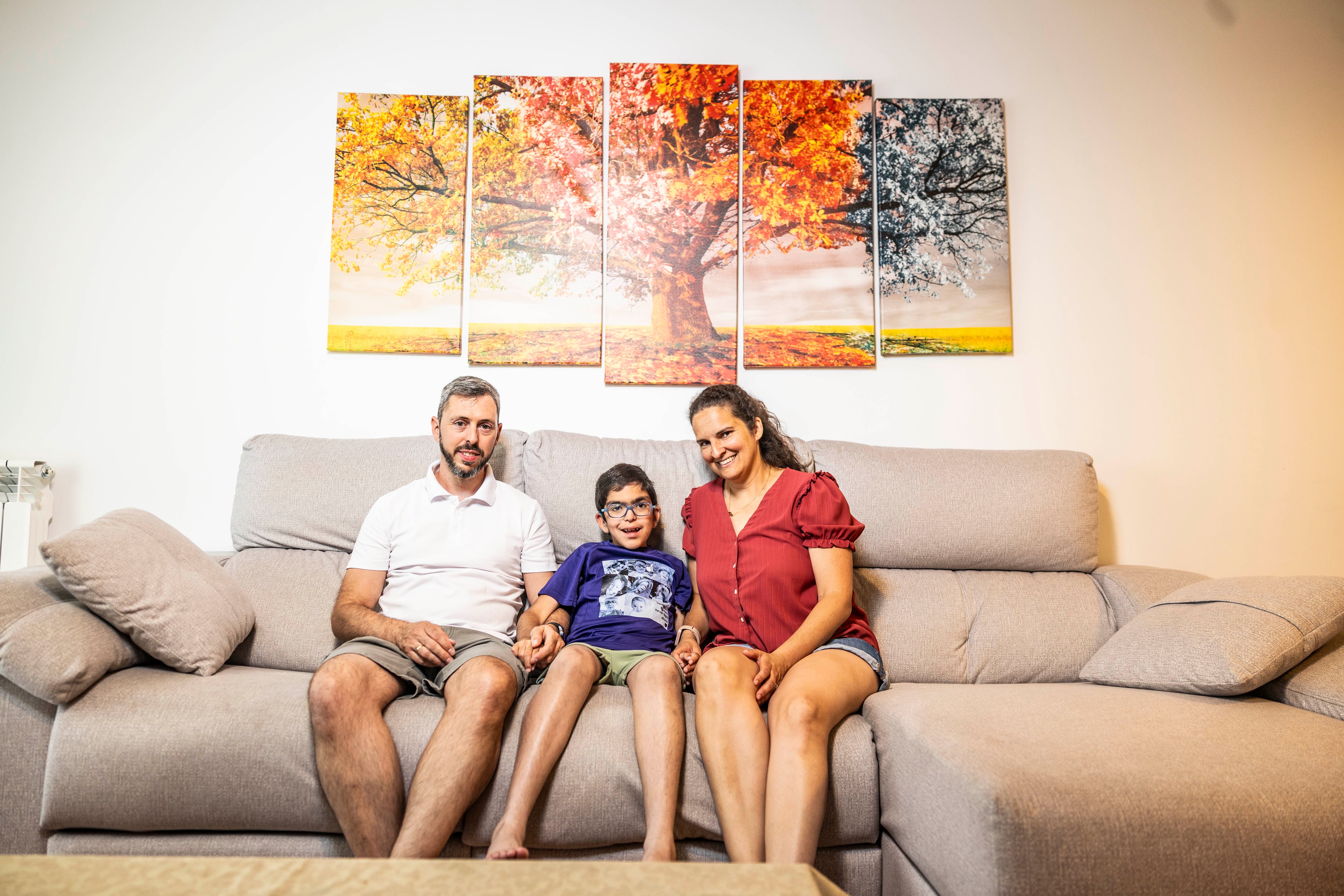 Gonzalo, de nueve años, posa con sus padres en su casa, en Madrid.