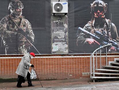 Una mujer camina delante de una tienda con carteles en los que aparecen soldados ucranios, este viernes en Kiev.