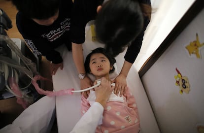 Los niños más pequeños de Koriyama, población cercana a la central nuclear de Fukushima, no saben lo que es jugar en la calle. En la imagen, un médico realiza un examen de la tiroides a una niña de cinco años de edad, en una clínica en el complejo de viviendas temporales en Nihonmatsu, en la prefectura de Fukushima.