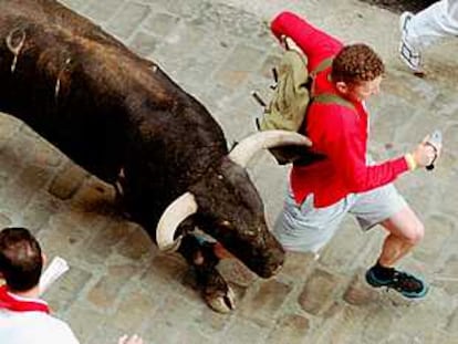 Un mozo corre junto a un toro, durante el quinto encierro.