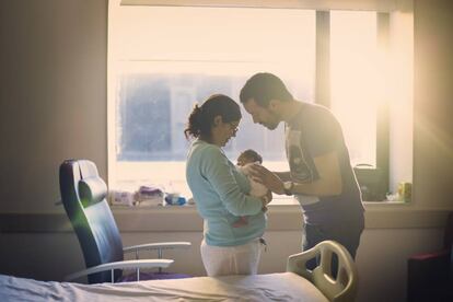 Dos padres miran a su recién nacido.