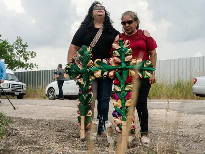 Dos mujeres de la comunidad donde se encontró el tráiler, lloran tras colocar cruces y velas, el 28 de junio.