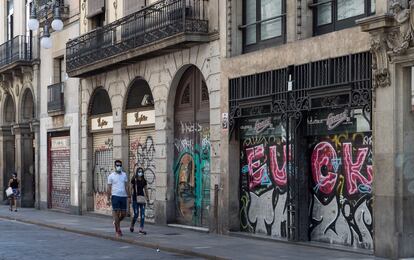 Una pareja pasea por la calle Ferran de Barcelona, con la mayoría de establecimientos cerrados.