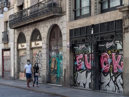 Una pareja pasea entre comercios cerrados en la calle Ferran de Barcelona.  Foto: Joan Sánchez