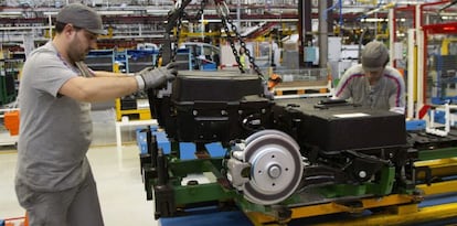 Dos operarios colocan las bater&iacute;as de la furgoneta el&eacute;ctrica Citro&euml;n Berlingo en la cadena de montaje de la planta de PSA. 