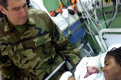 El ginecólogo militar José Sánchez Jordá observa al bebé recién nacido en el barco español.