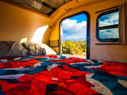 Cama dentro de una caravana ubicada en plena naturaleza.