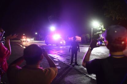 Curiosos fotografam a ambulância que transporta uma parte dos meninos resgatados