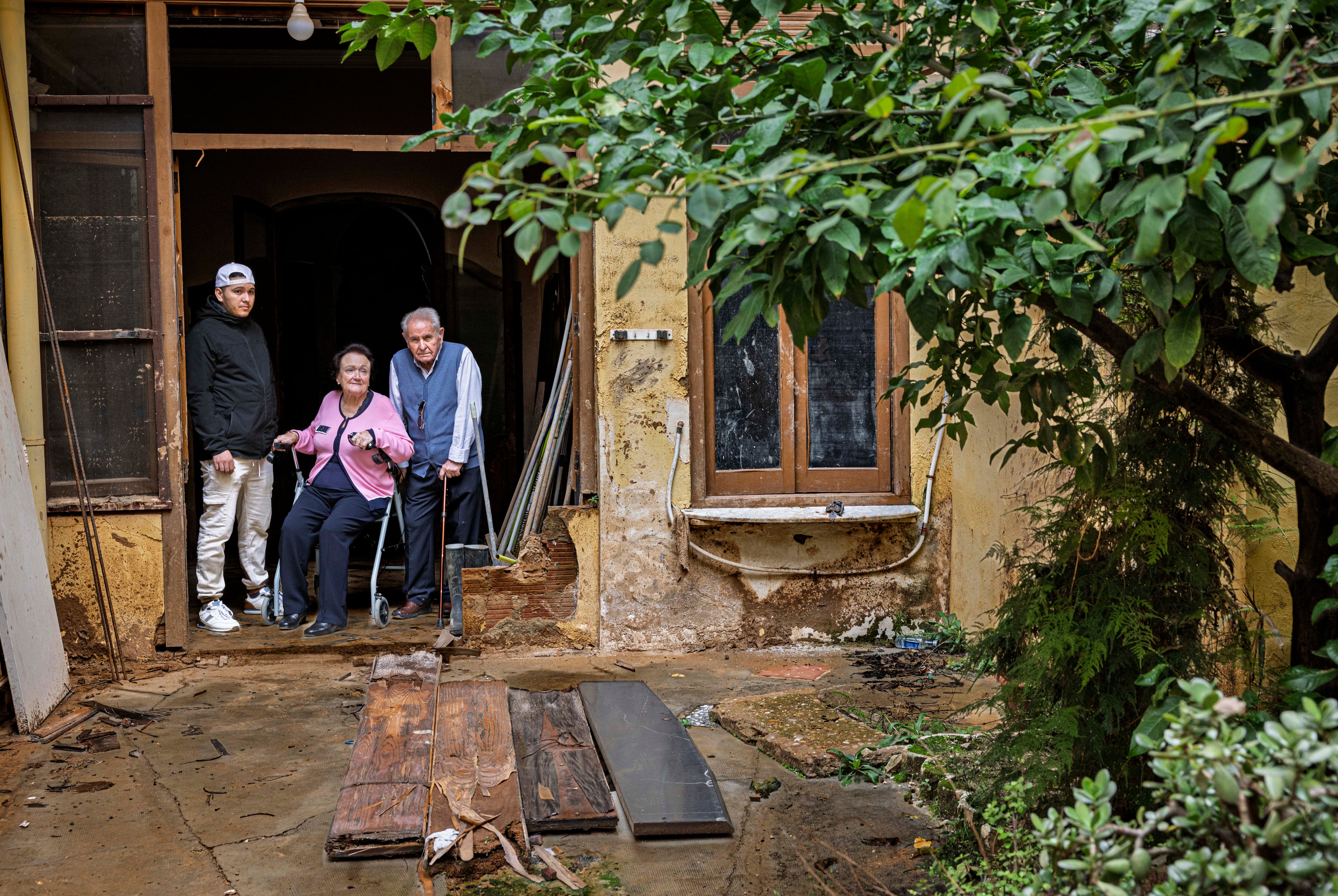 Wilfredo, Carmen y Daniel, frente al limonero del patio de su casa de Benetusser, donde la mujer fue rescatada el día de la dana. 