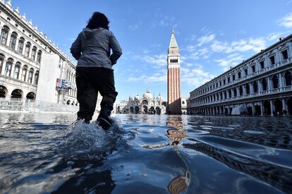 Una mujer camina por la Plaza de San Marcos inundada en Venecia.   