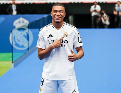 Mbappé points to the Real Madrid crest during his presentation. 