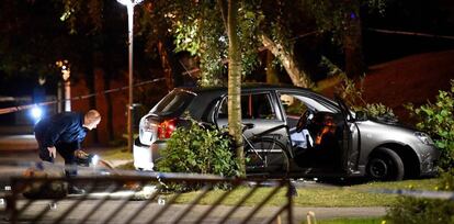 Un polic&iacute;a examina el coche contra el que un motorista ha disparado este domingo en Malmoe (Suecia). 