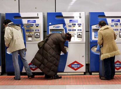 Tres personas compran billetes para entrar en el metro.