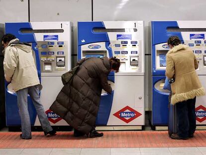 Tres personas compran billetes para entrar en el metro.