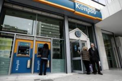 Un hombre retira dinero de un cajero automático de una sucursal del Banco de Chipre en Atenas (Grecia) hoy.