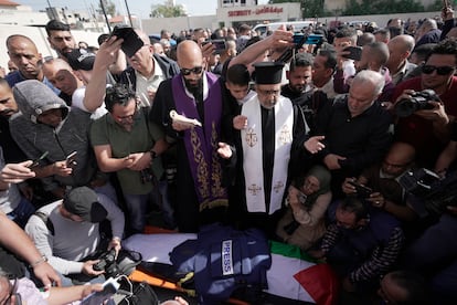 Sacerdotes cristianos rezan sobre el cuerpo de Shireen Abu Akleh, rodeados de otros periodistas, en Yenín (Cisjordania), este miércoles. El Gobierno israelí asegura que su muerte se debe “probablemente” a fuego de fuerzas palestinas. Otro reportero, Ali Samudi, resultó herido en la misma incursión.