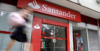 Una mujer camina delante de una oficina de Banco Santander.