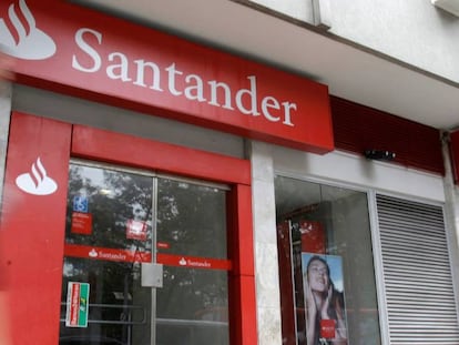 Una mujer camina delante de una oficina de Banco Santander.