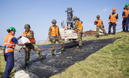 Vários soldados colaboram para reforçar um dique na Holanda.