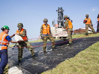 Vários soldados colaboram para reforçar um dique na Holanda.