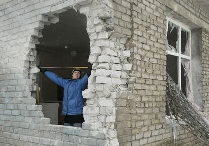 Una mujer inspecciona uno de los agujeros de un edificio dañado por los bombardeos que han tenido lugar en la ciudad de Donetsk (Ucrania), controlada por los rebeldes.