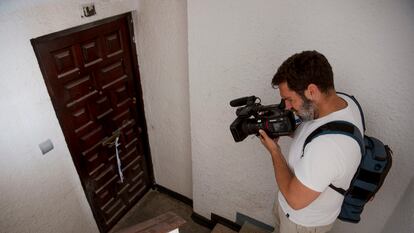 Un reportero de televisión toma imágenes de la puerta de la vivienda de Fuengirola, donde un hombre de 50 años ha muerto y una joven de 19 ha resultado herida al ser apuñalados este miércoles por la noche.