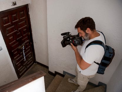 Un reportero de televisión toma imágenes de la puerta de la vivienda de Fuengirola, donde un hombre de 50 años ha muerto y una joven de 19 ha resultado herida al ser apuñalados este miércoles por la noche.