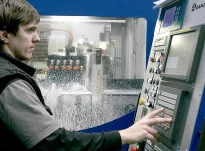 Un joven trabajador maneja una máquina en la empresa Danobat, del Grupo MCC.