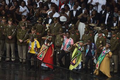 La gente baila delante de los soldados durante la ceremonia en memoria de Sudáfrica el expresidente Nelson Mandela.