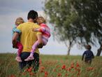 Un padre pasea con sus hijos por el campo.