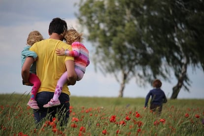 Un padre pasea con sus hijos por el campo.