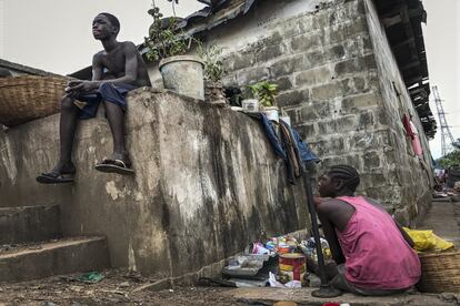 Fatimata junto al hierro que utiliza para chafar latas. Arriba, su hermano Nashir en Freetown, Sierra Leona.
