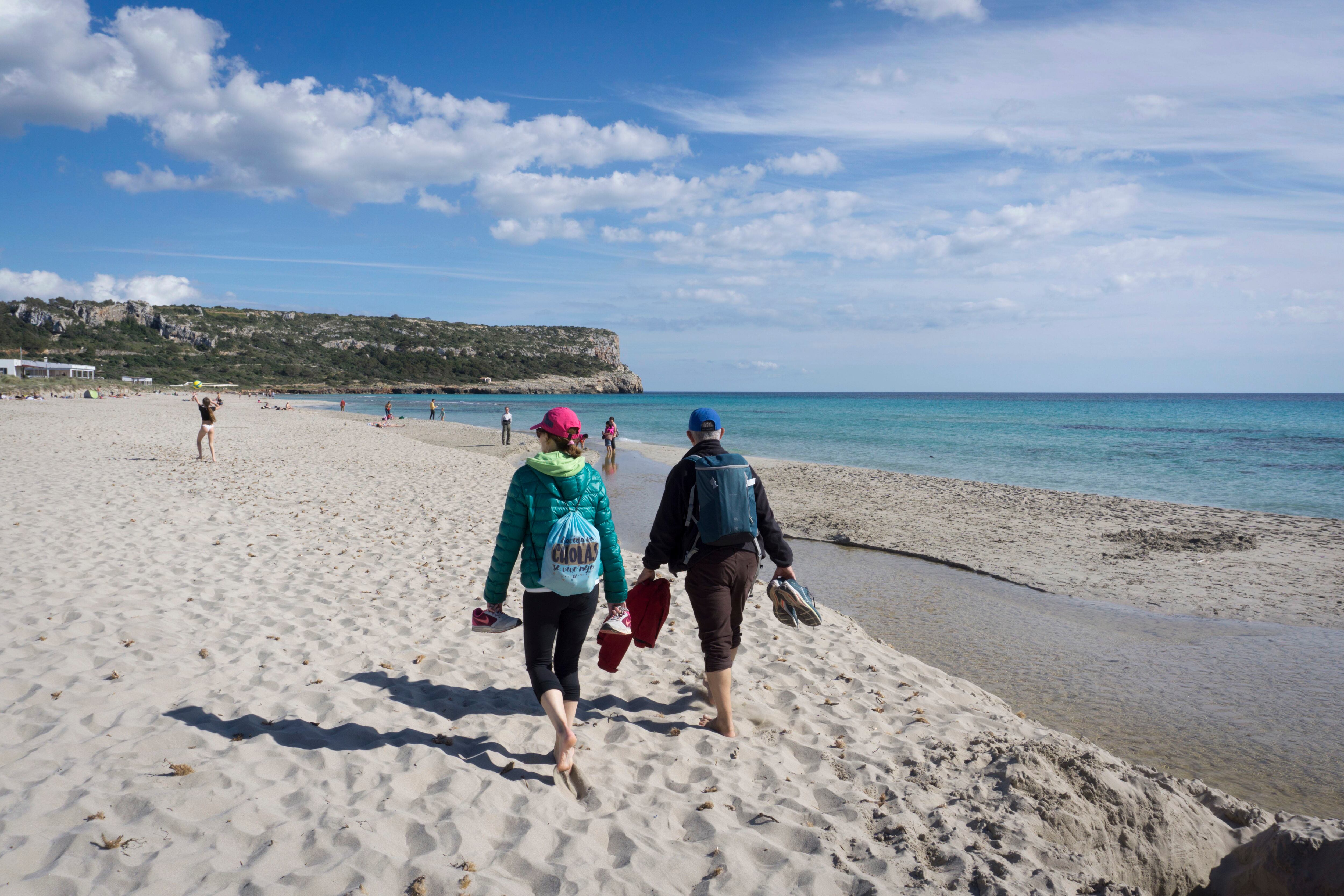 Varios turistas disfrutan de su primer día de vacaciones este Jueves Santo en la playa de Son Bou en Alaior, Menorca.