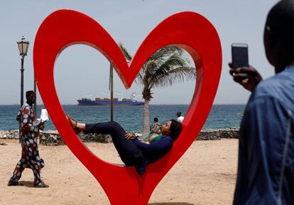 Una mujer senegalesa posa para una fotografía con un barco de mercancías de fondo, frente a la isla de Goree, frente a las costas de Dakar, Senegal.