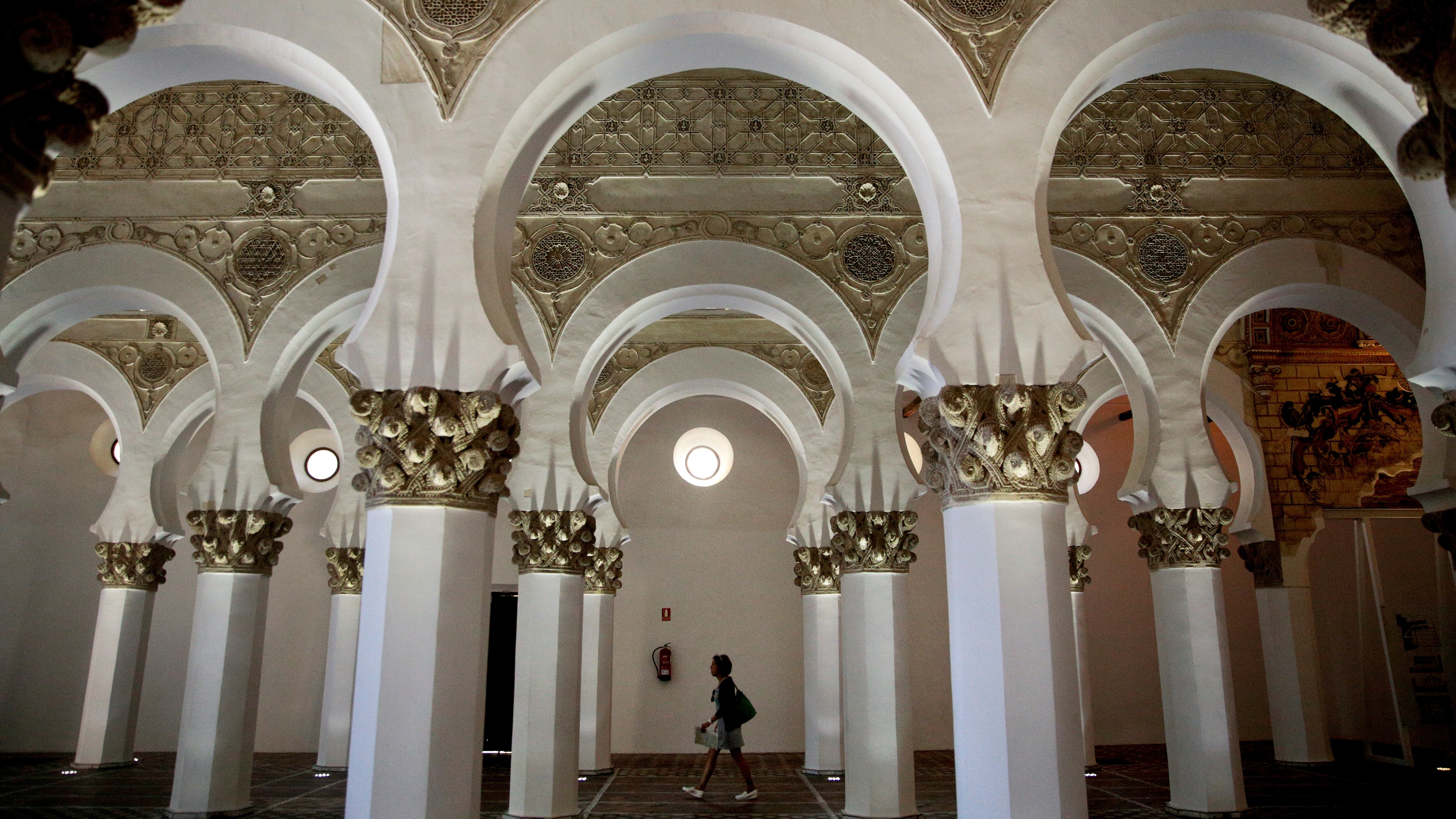 Una mujer camina por el interior de la sinagoga Santa María la Blanca en Toledo.