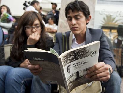 Dos j&oacute;venes leen un libro de Garc&iacute;a M&aacute;rquez frente a la funeraria donde est&aacute;n sus restos.