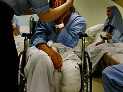 Una mujer a quien le han amputado una pierna es consolada en un hospital.